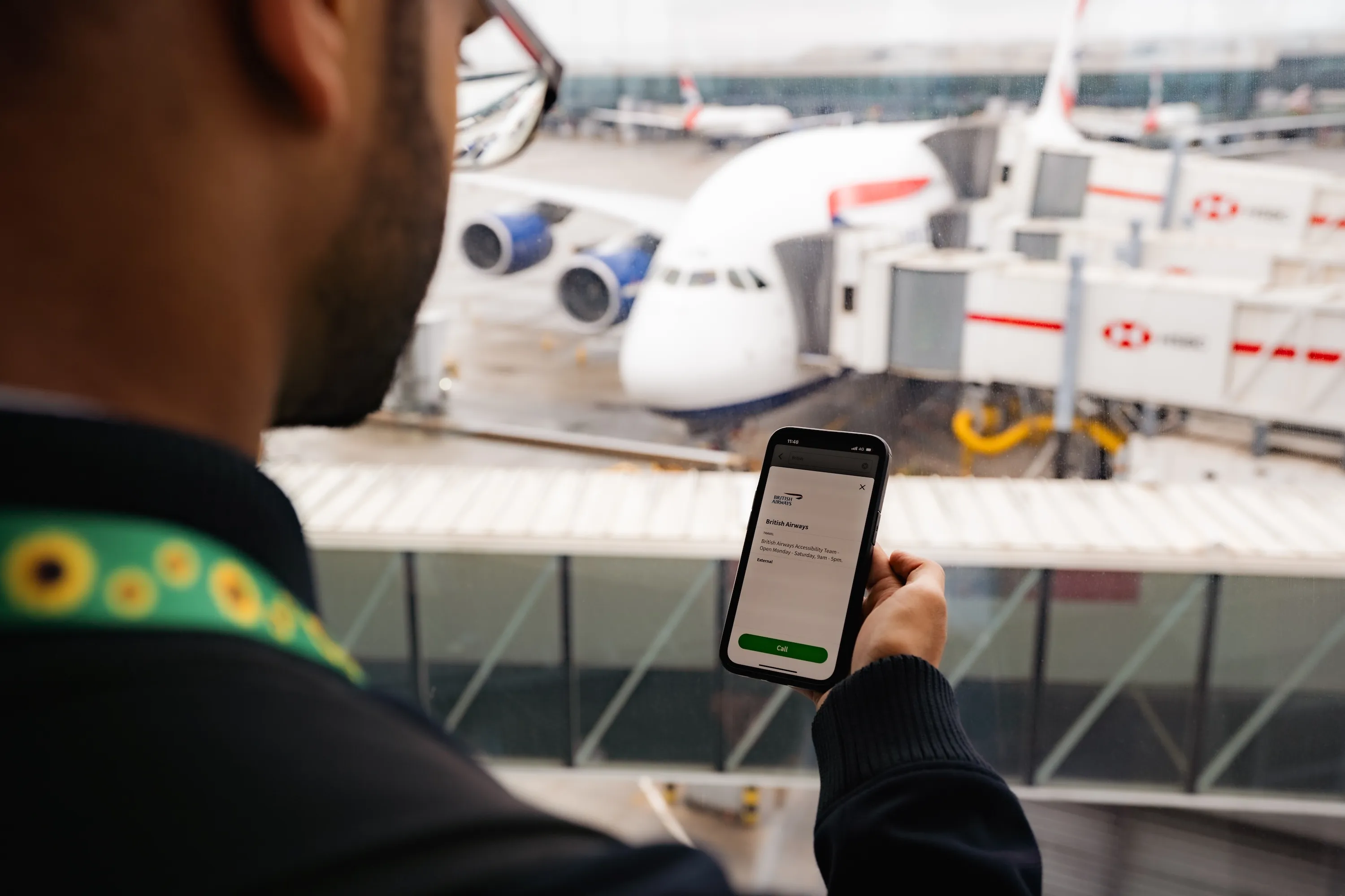 A traveller with a hidden-disabilities sunflower lanyard opening the accessibility contact screen by an A380