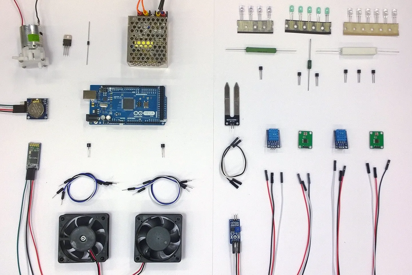 The kit's electronic components arranged flat: Arduino board, fans, moisture sensors, wiring and grow LEDs