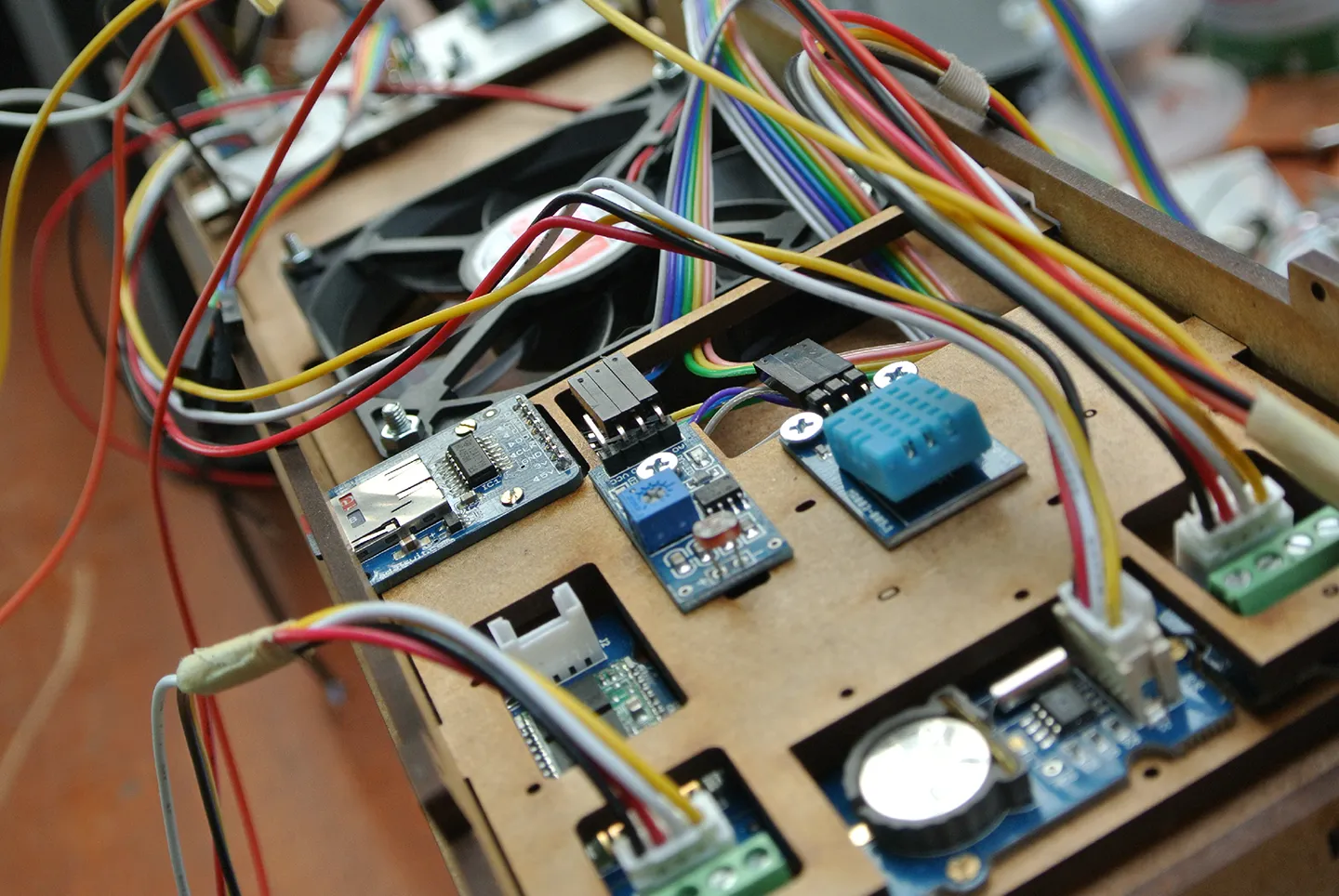 The assembled control board wired into the greenhouse frame, with sensor module and cooling fan in place